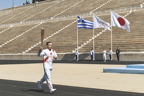 ◎ 三月十九日,希臘藝術體操運動員彼得羅尼亞斯手持聖火火炬跑入體育場。二0二0年東京奧運會火炬交接儀式在希臘雅典帕納辛奈科體育場舉行。(新華社)