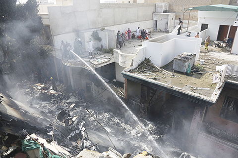 撲火 ◎ 五月二十二日,巴基斯坦國際航空公司一架載有一百零七人的客機當天下午在巴南部港口城市卡拉奇一處民居墜毀。圖為消防員在撲火。(美聯社)