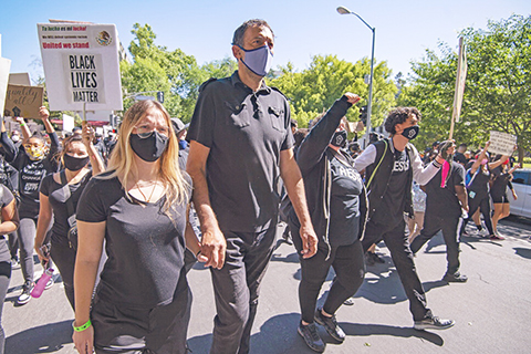 ◎ 帝王隊總經理迪瓦茨(前排左二)與示威者手牽手遊行,抗議種族歧視至費洛伊德死亡。(美聯社)