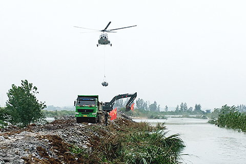 ◎ 七月十六日下午,湖北陽新富河幹流率洲管理區(軍墾農場)葵賽湖段下垸潰口處上空,一架米-171重型運輸直升機通過吊裝網兜、空投石塊等方式封堵潰口。(中新社)