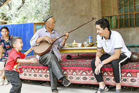 ◎ 7月19日,阿拉帕提·牙森(右)一家回鄉下看望父母。喜歡樂器的父親牙森·艾沙常常會為家人彈奏一曲。