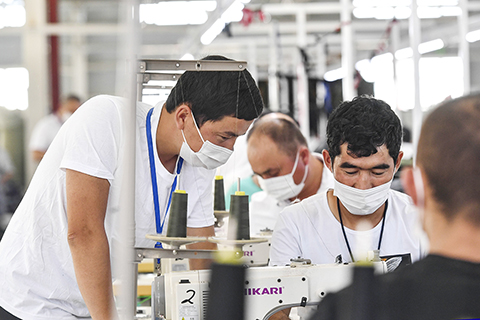 ◎ 7月20日,阿拉帕提·牙森(左)在車間裡指導自己班組的一名工友工作。