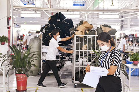 ◎ 7月20日,阿拉帕提·牙森(左)推著一車物料經過妻子古麗斯坦·艾山(右)的辦公區域。