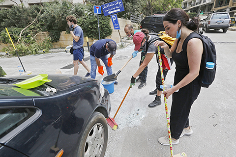 清理玻璃 ◎ 八月六日,在黎巴嫩首都貝魯特街頭,志願者幫助清理爆炸造成的碎玻璃等。(新華社)