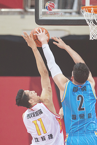 ◎ 十二月二十四日,深圳馬可波羅隊球員沈梓捷(左)在比賽中投籃。最終以一百比八十四戰勝北京首鋼隊。(新華社吳壯 攝)