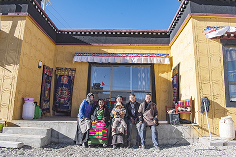 ◎ 旦增措姆和家人在新家門前(2月25日攝)。(新華社記者 孫非 攝)