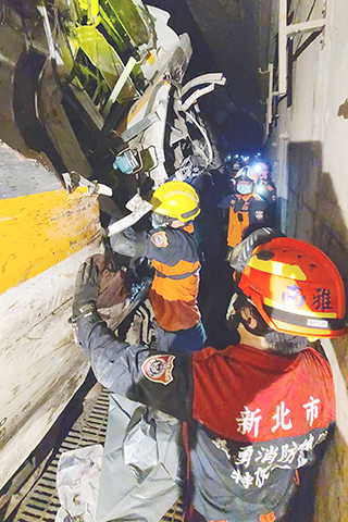 ◎ 台鐵中速度較快的列車,遭邊坡滑落的工程車撞上,發生出軌意外。圖為消防人員搶救受困乘客。(香港中通社)
