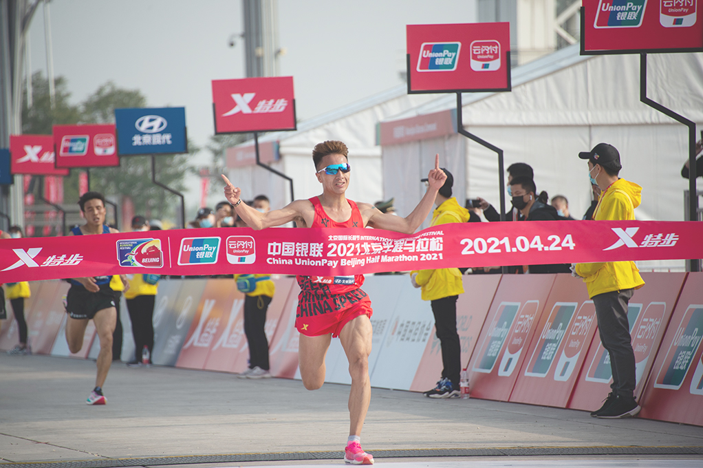 ◎ 四月二十四日,參賽選手彭建華衝過終點。當日,在二0二一年北京半程馬拉松賽中,彭建華以一小時四分五十三秒的成績獲得男子組第一名。(新華社記者陳鍾昊 攝)
