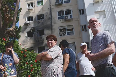 ◎ 當地時間五月十日至十一日,加沙地帶的武裝人員向以色列發射超過二百枚火箭彈。圖為五月十一日,在以色列南部城市阿什凱隆,人們聚集在遭遇加沙地帶火箭彈襲擊的樓房外。(新華社/基尼圖片社)