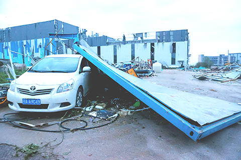 ◎ 圖為十五日,現場吹倒的工棚和受損的車輛。(中新社)