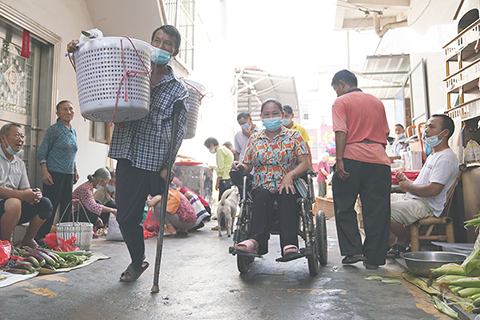 ◎ 本月十二日,袁長明挑著花生和妻子穿行在市集。