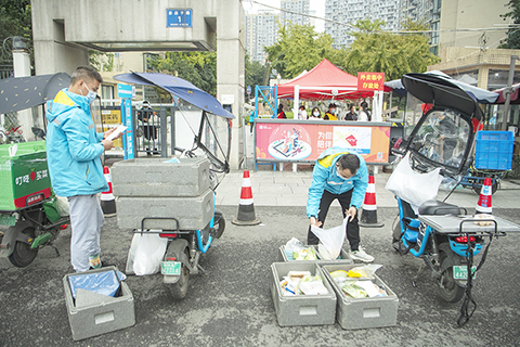 ◎ 十一月三日,成都市金牛區頂峰水岸匯景小區大門外,外賣小哥將居民訂購的生活物品裝袋後交小區志願者轉送。四川省二日已將成都市金牛區營門口街道頂峰水岸匯景小區(一期、二期)劃定為中風險區。(中新社)
