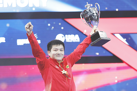 ◎ 中國選手樊振東在休斯敦世乒賽男子單打頒獎儀式上手捧獎杯慶祝勝利。在美國休斯敦舉行的世界乒乓球錦標賽男子單打決賽中,樊振東戰勝瑞典小將莫雷加德,獲得冠軍。(中新社記者 劉關關 攝)