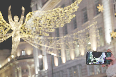 　◎ 行人在英國倫敦市中心點亮彩燈的攝政街上拍照。
