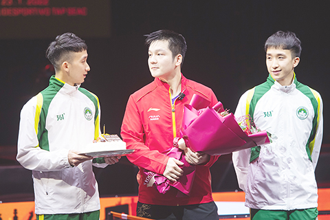 　◎ 一月二十二日，中國澳門乒乓球運動員張子澄（左）、張子浚（右）向適逢生日的樊振東送上鮮花和蛋糕。（新華社記者 張金加 攝）