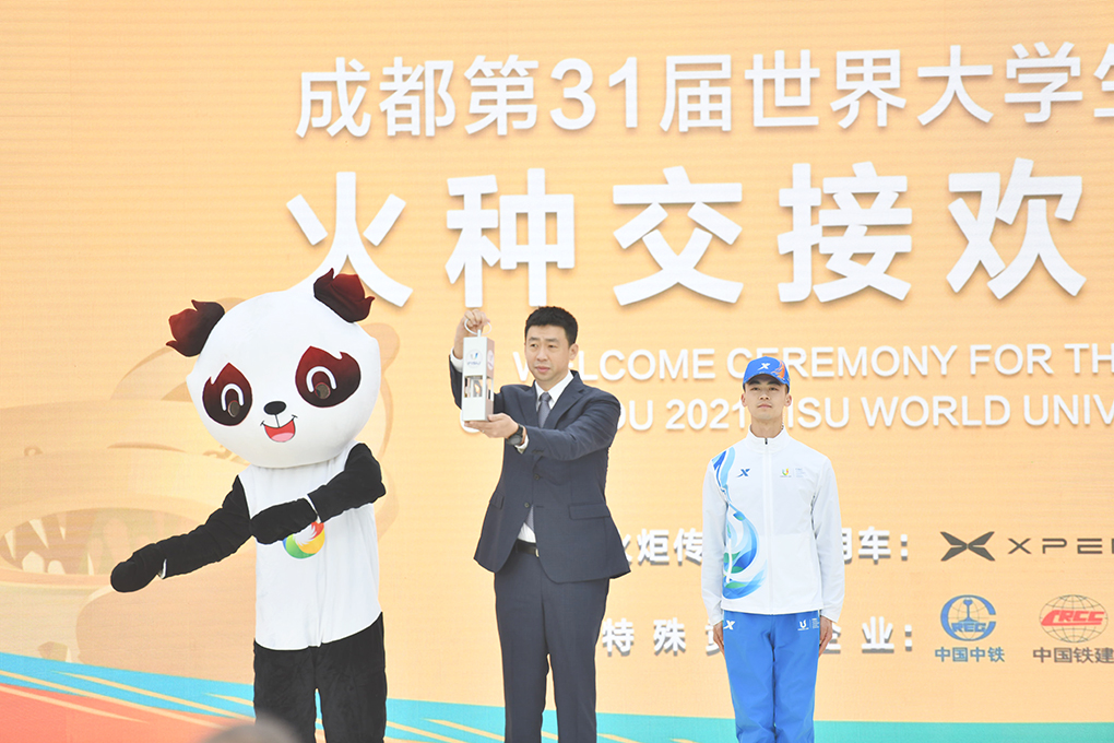 ◎ 二月二十五日,成都第三十一屆世界大學生夏季運動會(簡稱「成都大運會」)火種交接歡迎儀式在成都金沙遺址博物館舉行。圖為國際大體聯副主席申震(中)將今年一月在首屆大運會舉辦城市意大利都靈採集的火種遞交給成都。(中新社記者 張浪 攝)