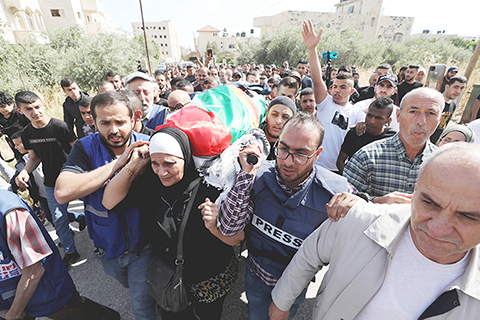 ◎ 圖為五月十一日,在約旦河西岸傑寧,人們在女記者的葬禮上抬著她的遺體。(新華社)