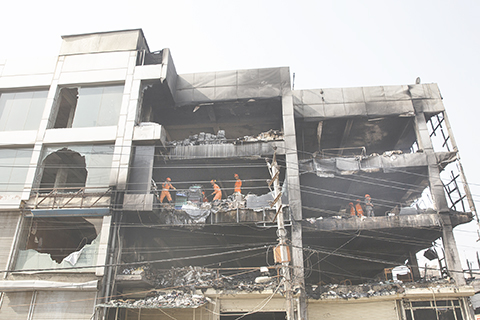 ◎據印度警方消息,首都新德里五月十三日發生的火災造成的死亡人數已上升到二十七人,另有數十人受傷。圖為十四日,救援人員在新德里發生火災的建築內工作。(新華社)