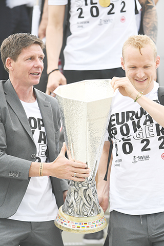 ◎ 法蘭克福隊年輕領隊加斯拿(左)手捧歐霸盃,昨晨返抵法蘭克福機場。(美聯社)