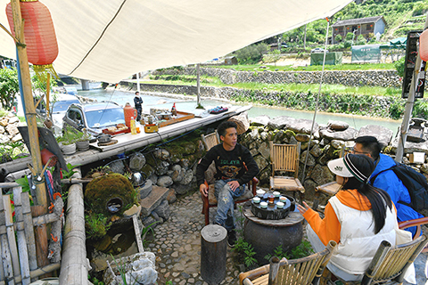 圖為5月17日,鄭心校(左一)在家門口與遊客喝茶聊天。(中新社記者 王東明攝)