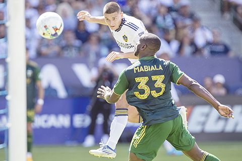 ◎ 當地時間六月十八日,在加利福尼亞州卡森舉行的美職聯足球比賽的下半場,洛杉磯銀河隊前鋒德揚.約維利奇(左)在波特蘭伐木者隊後衛拉里斯.馬比亞拉的防守下,頭球攻門。戰事呈膠著,是役以一比一打成平手。(美聯社/亞歷克斯加拉多)