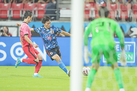 ◎ 七月二十七日,日本隊球員相馬勇紀(中)射門命中剎那。當日,在日本愛知縣豐田市舉行的二0二二東亞杯男子足球第三輪比賽中,日本隊以三比0戰勝韓國隊,從而以二勝一平的戰績獲得冠軍。(新華社記者 張笑宇 攝)