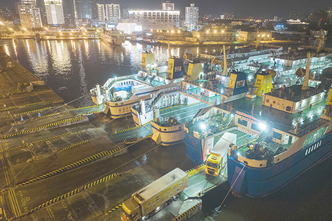 ◎ 八月二十四日,在海口港客運站碼頭,停航前抵港的客滾船正在卸船。當日二十時,受颱風「馬鞍」影響,海口新海港、秀英港、鐵路南港停止作業。(無人機照片)(中新社)
