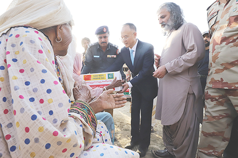 ◎ 九月十一日,在巴基斯坦西南部俾路支省德拉布格蒂,中國駐巴基斯坦大使農融(中)向當地受災群眾發放中國援助的救災物資。(新華社)
