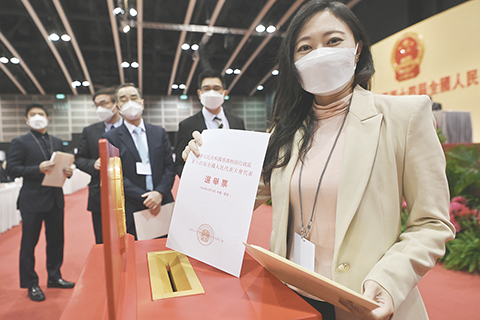 ◎ 十二月十五日上午,香港特區第十四屆全國人大代表選舉會議在香港舉行第二次全體會議。差額選舉產生了三十六名香港特區第十四屆全國人大代表。圖為選舉會議成員準備投票。(中新社記者 李志華 攝)