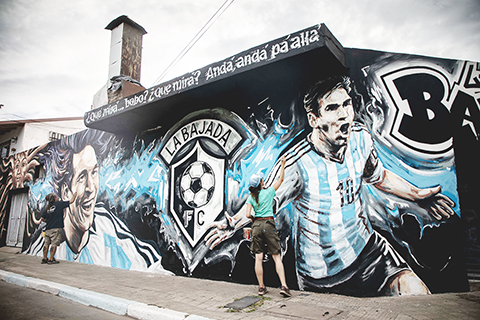 ◎ 十二月二十一日,壁畫藝術家利桑德羅.烏特亞加和搭檔馬琳.蘇里亞加在阿根廷羅薩里奧的拉巴哈達街區繪製一幅以美斯為主題的壁畫。(新華社發)