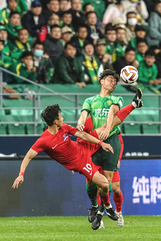 ◎ 四月十五日,梅州客家隊球員尹鴻博(左)與北京國安隊球員李磊在比賽中爭搶。在北京工人體育場舉行的中國足球協會超級聯賽第一輪比賽中,北京國安隊主場以一比一戰平梅州客家隊。(新華社記者 彭子洋 攝)