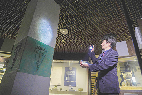 ◎ 近日,廣西柳州博物館館長程州演示日光鏡的神奇效果。(中新社記者 韋國政 攝)