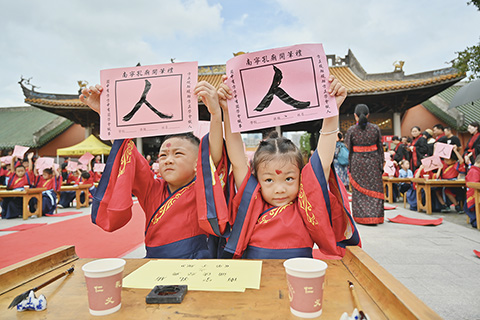 ◎ 六月二十二日,一場「開筆禮」活動在廣西南寧市孔廟舉行。活動現場,孩童通過禮拜孔子、描紅書寫「人」字、誦讀經典等方式,感受中華傳統文化。圖為小朋友們展示各自寫的「人」字。(中新社)