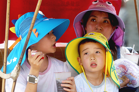 ◎ 六月二十三日,北京什刹海,遊人防曬出行。當日,北京市氣象台升級發佈高溫紅色預警信號。(中新社記者 張宇 攝)