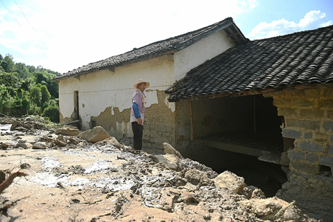 ◎ 七月五日,在重慶萬州長灘鎮一村莊,一位老人在查看自己家受災情況。(中新社)