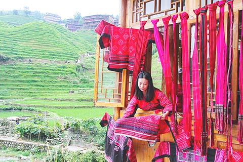 ◎ 七月廿三日,廣西桂林市龍勝各族自治縣龍脊鎮大寨村舉行一年一度的「六月六曬衣節」,紅瑤阿嫂在木樓上掛曬紅衣。(楊宗盛攝)