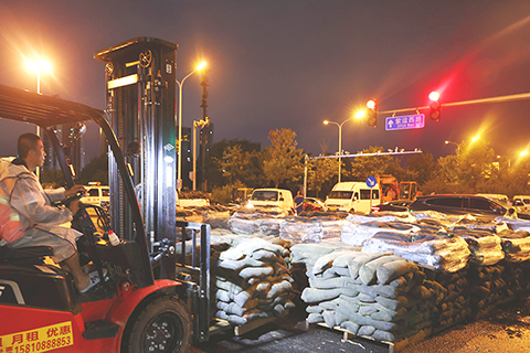 ◎ 七月三十日,北京防汛相關工作人員在京杭大運河河堤路段準備物資備勤。當日白天到夜間,北京維持暴雨紅色預警信號,持續防汛紅色(一級)預警響應。(中新社記者 楊可佳攝)