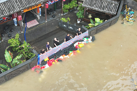 ◎ 七月三十日上午,在今年第五號颱風「杜蘇芮」過後,福建省終止防颱風應急響應與防暴雨應急響應,生產生活秩序正在有序恢復。據福建省防汛辦通報,截至七月二十九日二十一時,「杜蘇芮」已造成福建一百四十五點四五萬人受災,直接經濟損失三十點五三億元人民幣。圖為七月二十九日,福州市區一家餐館工作人員在門口關注積水情況。(無人機照片)(中新社記者 王東明 攝)