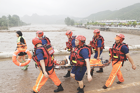 ◎ 八月一日,北京門頭溝區妙峰山鎮水峪嘴村,消防隊員轉移行動不便的老人出村。七月二十九日以來,北京地區持續強降雨,西南部降雨量大,妙峰山鎮水峪嘴村受災嚴重。(中新社記者 盛佳鵬 攝)