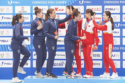 ◎ 八月六日,第三十一屆世界大學生夏季運動會擊劍項目女子花劍團體金牌賽在四川成都舉行,中國隊四十五比二十二擊敗意大利隊獲得金牌。圖為中國隊(紅白衣)和意大利隊在頒獎儀式上互相慶祝。(中新社記者 瞿宏倫 攝)