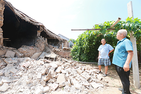 ◎ 八月六日,山東德州市平原縣震中地區的村民正在查看一處倒塌的沒有人居住的危房,防止發生二次傷害。(中新社記者 梁犇 攝)