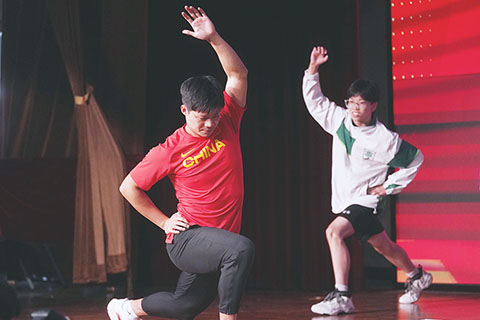 ◎ 十月十二日,在香港培僑中學,中國短跑名將蘇炳添與學生在互動前熱身。(新華社 王申 攝)