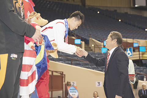 ◎ 當地時間十一月十七日,在美國得州沃斯堡舉行的第十六屆武術世錦賽首日比賽中,中國選手劉釗赫以九點八二三分奪得男子刀術冠軍。圖為恒源祥集團創始人劉瑞旗為劉釗赫頒獎。(中新社記者 廖攀 攝)