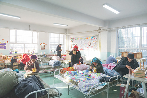 ◎ 十二月二十日,受災民眾在青海民和中川鄉美一小學安置點教室內吃早飯。積石山六點二級地震導致青海省海東市民和縣中川鄉受災嚴重,部份受災民眾在中川鄉美一小學得到妥善安置,入住教學樓或帳篷,現場生活物資儲備充足,秩序井然。(中新社記者 馬銘言 攝)