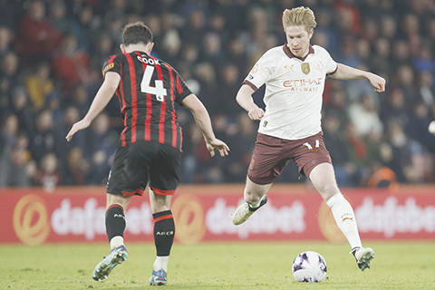 ◎ 二月二十四日,在英格蘭伯恩第斯活力體育場舉行的般尼茅夫和曼城之間的英超足球比賽中,曼城隊迪布尼帶球試圖穿越般尼茅夫隊確克的攔截。(美聯社/大衛克裡夫)