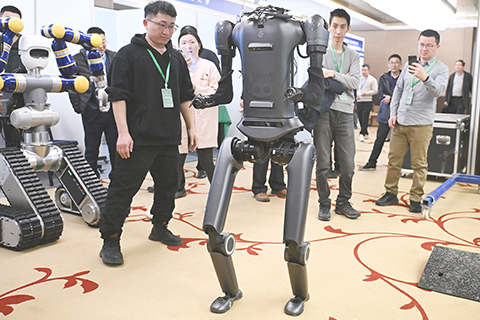 ◎ 三月十三日,工作人員向參觀者展示一款人形機器人。當日,由中國人形機器人百人會主辦的人形機器人大賽在北京經濟技術開發區正式開賽。(中新社記者田雨昊 攝)