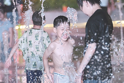 ◎ 八月三日晚,江蘇淮安,小朋友在街頭噴泉處戲水覓清涼。當日,江蘇省氣象台繼續發佈高溫橙色預警,預計八月四日,全省大部份地區日最高氣溫達攝氏三十七度以上。(中新社記者 泱波 攝)