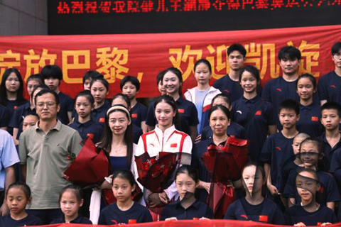 ◎ 八月十六日,在巴黎奧運會藝術體操集體全能項目中與隊友一同摘得金牌的浙江小將王瀾靜返回杭州,浙江體育職業技術學院為其舉辦歡迎儀式。圖為王瀾靜(白衣)與眾人合影。(中新社記者 蕭健 攝)