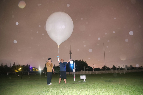 ◎ 九月十五日,颱風「貝碧嘉」登陸上海概率不斷增大。當晚,十九點十五分,上海市寶山區氣象局的氣象專家準時釋放「探空氣球」,監測颱風數據。據介紹,「探空氣球」能飛到三萬米高空,對大氣壓力、濕度、風速風向等氣象要素進行測量,有助於判斷颱風的最新動向。圖為氣象專家接收放飛指令。(中新社記者張亨偉 攝)