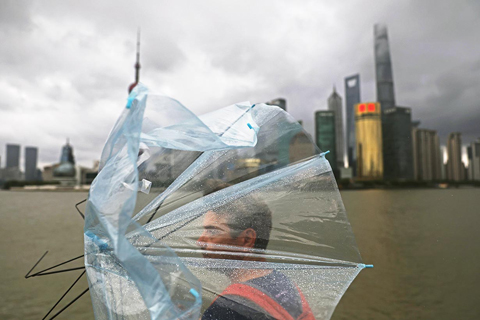 ◎ 九月十五日,在上海外灘濱江步道上,外籍遊客的雨傘被大風吹起。當晚十八時,中央氣象台發佈颱風紅色預警:今年第十三號颱風「貝碧嘉」的中心九月十五日十七時位於上海市東偏南方大約四百三十五公里的東海海面上,中心附近最大風力有十三級。預計,「貝碧嘉」將以每小時二十至二十五公里的速度向偏西方向移動,強度還將有所加強,穿過舟山群島後,將於九月十六日早晨至上午在浙江舟山到江蘇啟東一帶沿海登陸(颱風級或強颱風